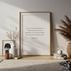 May include: A framed print with a light wood frame displays the text "If any of you lacks wisdom, you should ask God..." in black font. The print is propped against a wall, with decorative items nearby.