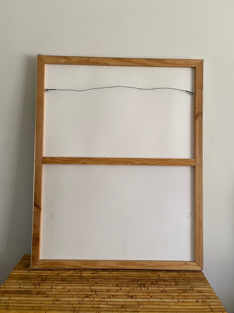 May include: The back of a framed canvas painting with a wooden frame. The frame has a wire attached to the top for hanging.