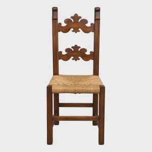 May include: A wooden chair with a dark brown finish featuring a high backrest with two horizontal slats, each adorned with a decorative carved scroll pattern. The seat is constructed from woven natural tan fiber, supported by four straight legs.