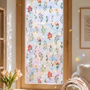 May include: A rectangular window film featuring a stained glass effect with a repeating pattern of red, orange, and yellow flowers interspersed with green leaves. The film has an iridescent, prismatic finish that reflects light in rainbow colours.