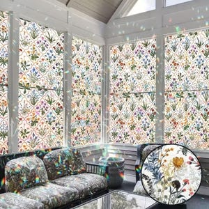 May include: A conservatory with windows adorned with floral patterned window film. The film displays a repeating pattern of colourful flowers and foliage on a white backdrop. The room features a sofa with patterned cushions and a glass-topped table.