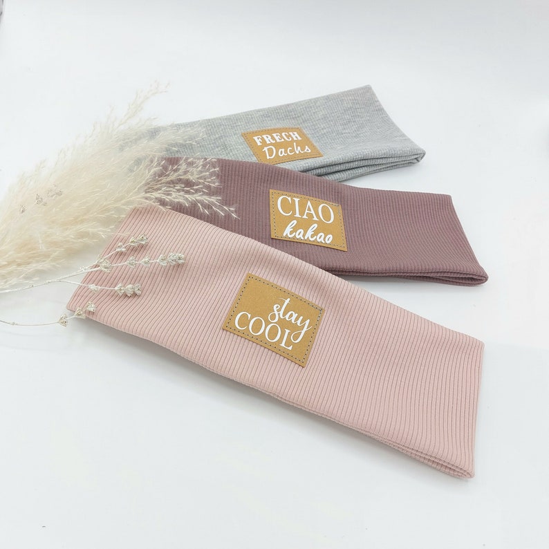 May include: Three fabric headbands with brown leather patches. The patches have white text that reads "Frech Dachs", "Ciao kakao", and "Stay Cool".