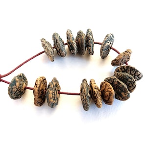 May include: A necklace with brown and black patterned beads strung on a dark red cord. The beads are arranged in a circular design. The beads have a textured surface, creating a unique look.
