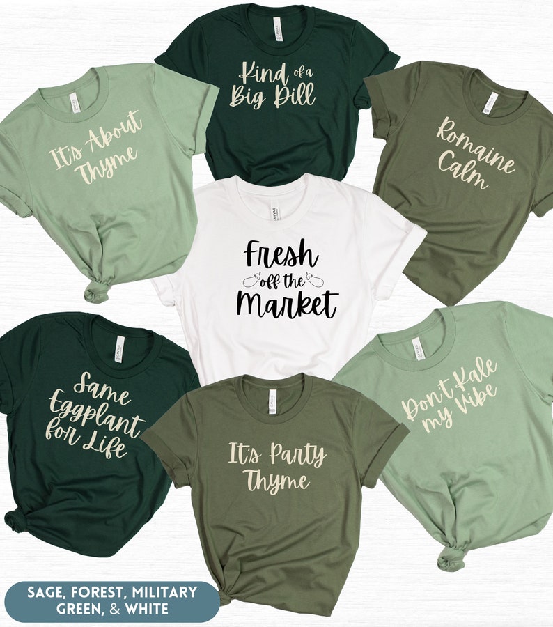 May include: Six different t-shirts with various vegetable puns. The shirts are in sage, forest, military green, and white colors. The text on the shirts reads: "It's About Thyme", "Kind of a Big Dill", "Romaine Calm", "Fresh Off the Market", "Same Eggplant for Life", "It's Party Thyme", and "Don't Kale My Vibe".