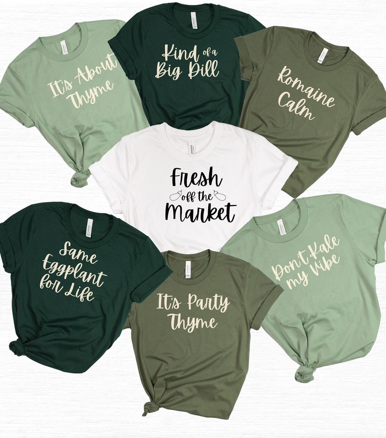 May include: Seven green, white, and olive green t-shirts with various vegetable-themed puns. The shirts feature the text: "It's About Thyme", "Kind of a Big Dill", "Romaine Calm", "Fresh off the Market", "Same Eggplant for Life", "It's Party Thyme", and "Don't Kale my Vibe".