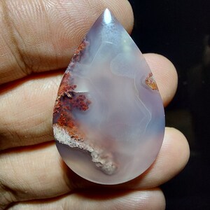 Peut inclure: Un cabochon d'agate en forme de larme avec un motif de couleur blanc, gris et rouge. L'agate a une surface lisse et polie.