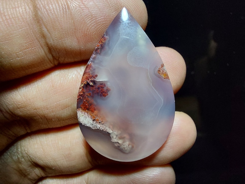 Peut inclure: Un cabochon d'agate en forme de larme avec un motif de couleur blanc, gris et rouge. L'agate a une surface lisse et polie.
