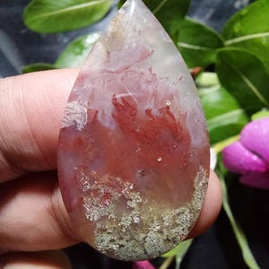 Op de afbeelding: Een traanvormige hanger gemaakt van rode, witte en groene agaat. De agaat heeft een uniek patroon van swirls en insluitsels.