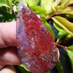 以下が含まれることがあります： 赤、白、茶色の模様が入った涙型の瑪瑙のカボション。瑪瑙は独特の質感のある表面をしています。