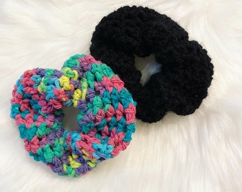 May include: Two crocheted hair scrunchies, one in a rainbow color pattern and one in black.