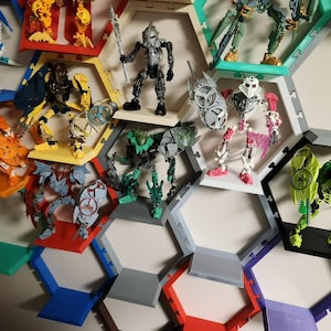 May include: A collection of articulated action figures displayed within a modular honeycomb-shaped wall shelving system. The shelves are constructed from colorful plastic segments in shades of red, yellow, green, blue, purple, and gray.
