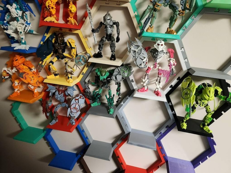 May include: A collection of articulated action figures displayed within a modular honeycomb-shaped wall shelving system. The shelves are constructed from colorful plastic segments in shades of red, yellow, green, blue, purple, and gray.