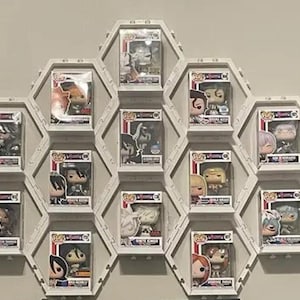 May include: A wall-mounted display of Funko Pop figures in individual hexagonal display cases. The cases are white and arranged in a honeycomb pattern. Each case contains a different figure, many with colorful designs.