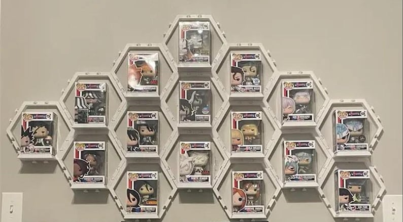 May include: A white modular honeycomb-shaped wall display system featuring multiple hexagonal compartments. Each individual section holds a single collectible vinyl figure inside its original square windowed cardboard packaging box.