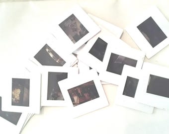 May include: A pile of white plastic slide frames with various images inside. The images are mostly dark and blurry.