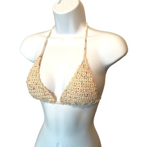 May include: A crocheted bikini top in a cream color with multi-colored flecks. The top is a triangle style with adjustable straps.