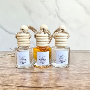 May include: Three glass bottles with wooden stoppers and gold cords. Each bottle contains a different scented oil diffuser: Lavender Patchouli, Blueberry Cobbler, and Clove & Sandalwood. Each bottle is labeled "Simply Made" and has a volume of 8 ml.