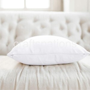May include: A white pillow with a zipper closure. The pillow is sitting on a white couch.