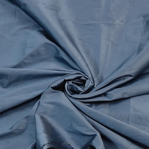 以下が含まれることがあります： 絹のような光沢のある滑らかな青い布のクローズアップ。布は折り畳まれ、ドレープされ、その質感とドレープが示されています。