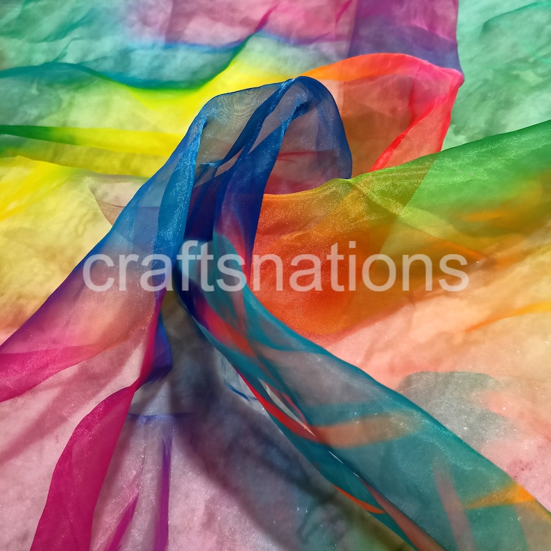 May include: A vibrant, sheer fabric in a rainbow of colors, including blue, pink, green, orange, and yellow. The fabric is layered and flowing, with the text "craftsnations" printed on it. The material appears lightweight and translucent.