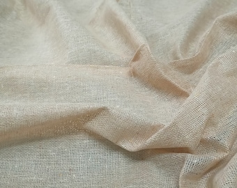 May include: A close-up of a beige, woven fabric with a textured surface. The fabric is folded and draped, creating soft folds and wrinkles.