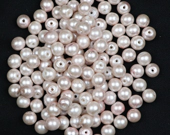 May include: A large pile of white pearl beads. The beads are round and smooth, and they are all about the same size.
