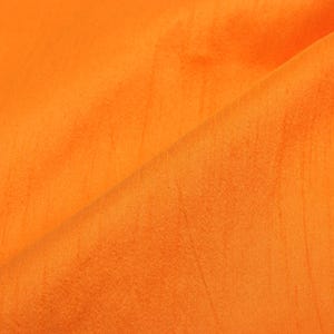 Könnte beinhalten: Nahaufnahme eines leuchtend orangefarbenen Stoffes mit einer glatten, leicht strukturierten Oberfläche. Der Stoff ist in der Mitte gefaltet und erzeugt eine diagonale Linie über das Bild.