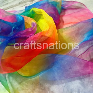 May include: A vibrant rainbow-colored sheer fabric with the text "craftsnations" in white. The fabric is arranged in flowing folds, showcasing a spectrum of colors including red, orange, yellow, green, blue, and purple.