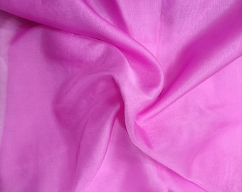May include: A close-up of a soft, pink fabric with a smooth, silky texture. The fabric is draped and folded, creating a flowing, elegant look.