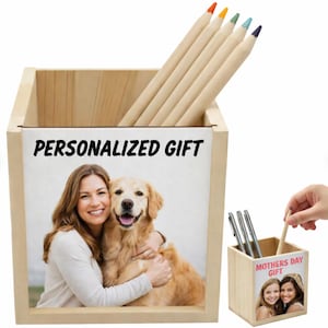 Op de afbeelding: Een vierkante houten pennenhouder met een afgedrukte foto van een persoon die een golden retriever knuffelt. De tekst "PERSONALIZED GIFT" staat in het zwart boven de foto. Een tweede weergave toont de houder met de tekst "MOTHERS DAY GIFT".