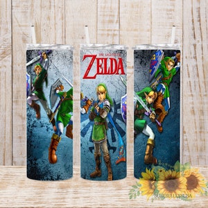 Könnte beinhalten: Drei Edelstahlbecher mit blauem Hintergrund und Bildern von Link aus der Videospielserie The Legend of Zelda. Der Text "The Legend of Zelda" ist auf dem mittleren Becher aufgedruckt.