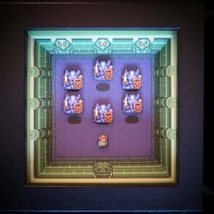 Op de afbeelding: Een videogamescherm met een personage in een paars en blauw pak dat in een groene en bruine kamer staat met zes andere personages in hetzelfde pak.