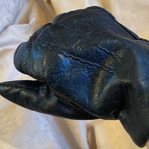 May include: A pair of black leather gloves with a stitched seam detail.