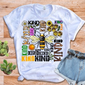 May include: White t-shirt with a bee and honeycomb design. The shirt has the word "Kind" repeated multiple times in different colors and fonts.