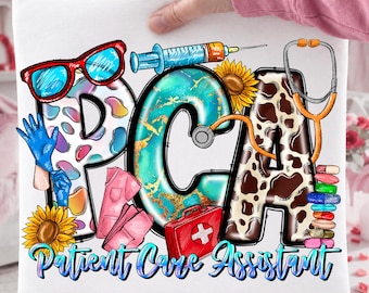 May include: White t-shirt with the letters "PCA" in a colorful design, featuring medical-themed illustrations. The design includes a stethoscope, syringe, and the words "Patient Care Assistant."