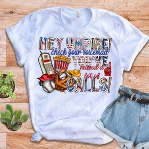 May include: White t-shirt with a baseball themed graphic that says "Hey Umpire! Check your voicemail you've missed a lot of calls!"