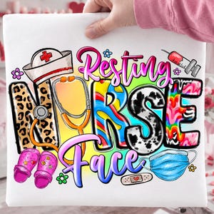 Könnte beinhalten: Weißes T-Shirt mit einem farbenfrohen Grafikdesign. Das Design zeigt die Worte "Resting Nurse Face" mit medizinischen Illustrationen wie Stethoskop, Spritze, Gesichtsmaske und Krankenschwestermütze.