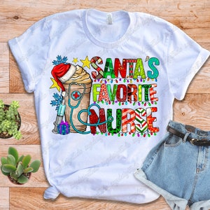 Puede incluir: Camiseta blanca con el texto "SANTA'S FAVORITE NURSE" en letras coloridas. El dise&ntilde;o incluye un gorro de Pap&aacute; Noel, una taza de caf&eacute;, un estetoscopio, una jeringa y una caja de regalo. La camiseta se combina con pantalones cortos vaqueros y un cintur&oacute;n.