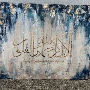 May include: Abstract painting with a blue and gold color scheme. The painting features Arabic calligraphy in gold paint and the text "Verily in the remembrance of Allah do hearts find rest".