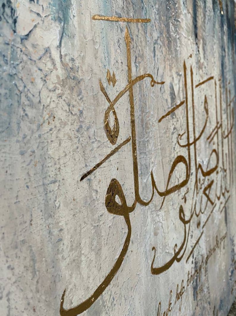 May include: A white canvas with a textured surface features gold calligraphy in Arabic script. The text reads "Love & help those around you".