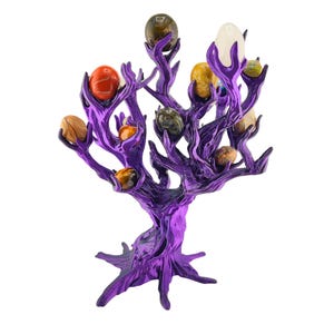 May include: A metallic purple tree-shaped display stand with multiple branches, each holding a smooth, polished, egg-shaped stone of varying colors including red, yellow, brown, white, and dark grey, arranged in a decorative, upright structure.