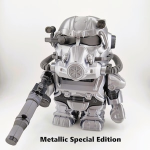 May include: A metallic silver figurine of a character in a futuristic suit, holding a gun. The figure has a detailed helmet with tubes and a circular emblem. The text "Metallic Special Edition" is printed at the bottom.