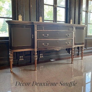 May include: A dark brown antique buffet with gold trim and accents. The buffet has three drawers and two side cabinets. The legs are ornate and gold. The text "Décor Deuxième Souffle" is at the bottom.