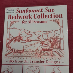 May include: A book cover featuring the title "Sunbonnet Sue Redwork Collection for All Seasons" and an illustration of two girls sitting on a porch. The book contains 16 iron-on transfer designs by Loyce Saxton.
