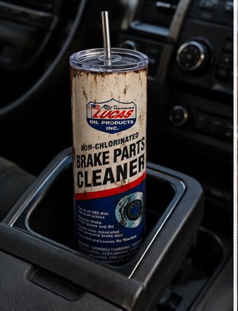 May include: A cylindrical tumbler with a clear lid and a metal straw, featuring a graphic design that mimics a Lucas Oil Products Non-Chlorinated Brake Parts Cleaner can. The design includes white, red, and blue colors with weathered, rusted textures.
