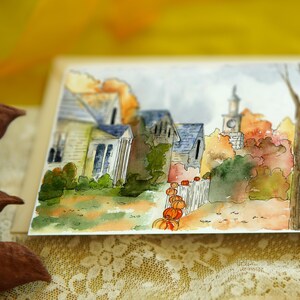 May include: Watercolour painting of a small town with houses and a church in the background. The houses are painted in shades of brown and grey, and the church has a white steeple. There are trees in the foreground, some of which are painted in shades of green and brown, and others are painted in shades of red and orange. There are pumpkins in the foreground, painted in shades of orange and yellow.