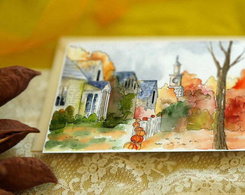 May include: Watercolour painting of a small town with houses and a church in the background. The houses are painted in shades of brown and grey, and the church has a white steeple. There are trees in the foreground, some of which are painted in shades of green and brown, and others are painted in shades of red and orange. There are pumpkins in the foreground, painted in shades of orange and yellow.