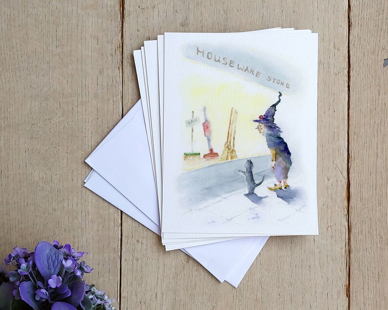 May include: A watercolor illustration of a witch and a black cat standing in front of a store called "Houseware Store". The witch is wearing a purple and black robe and a pointed hat. The cat is looking up at the witch.