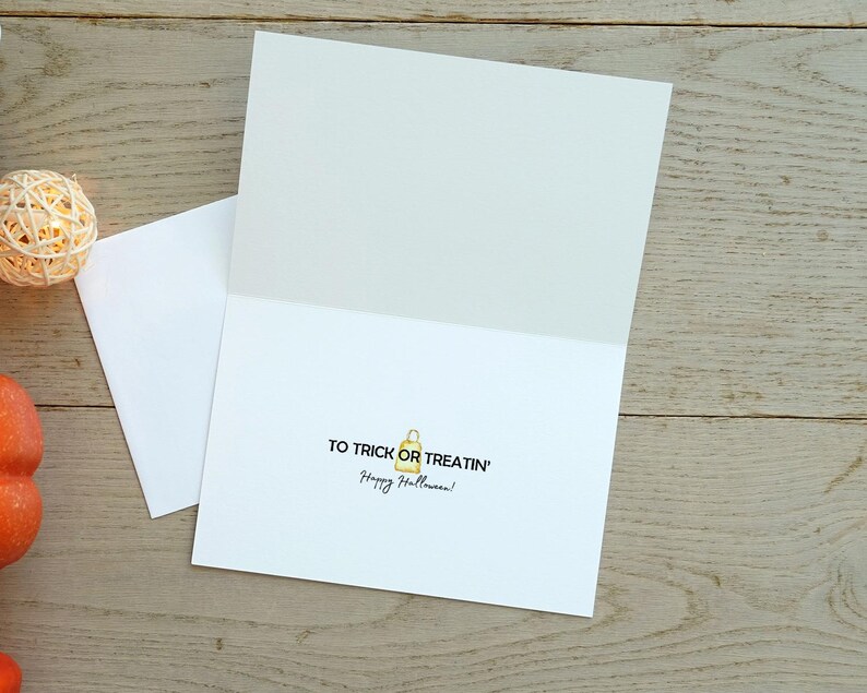 May include: A white card with the text "To trick or treatin' Happy Halloween!" and a small yellow illustration of a trick-or-treat bag.