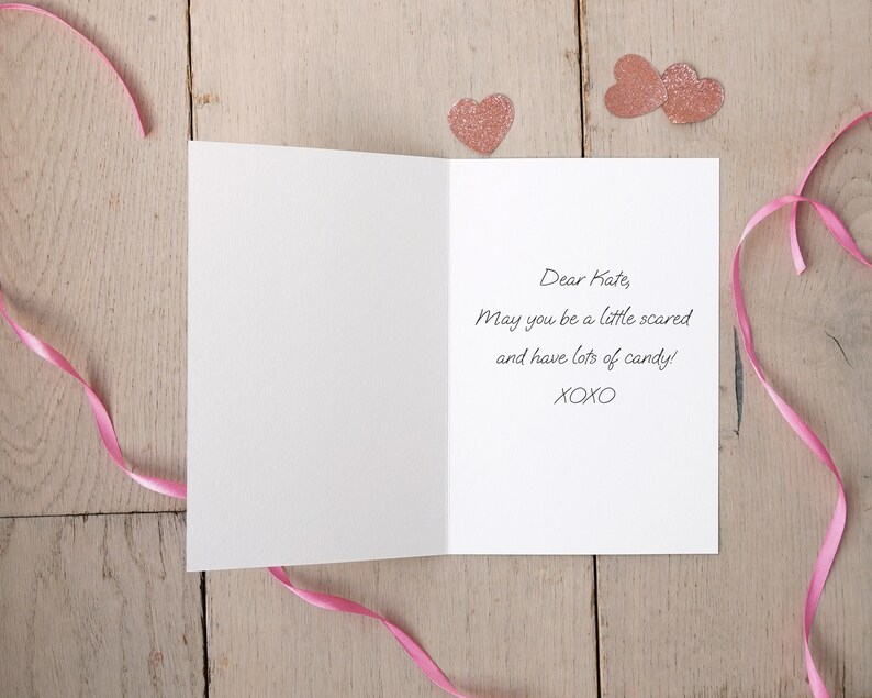 May include: A white card with a pink ribbon and pink glitter hearts. The card reads "Dear Kate, May you be a little scared and have lots of candy! XOXO"